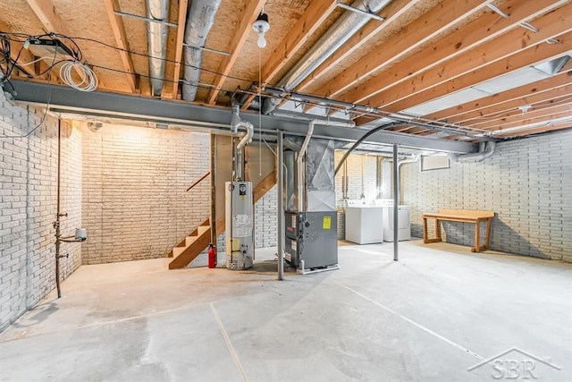 unfinished below grade area featuring gas water heater, brick wall, washer and dryer, stairway, and heating unit