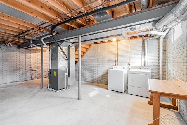 unfinished basement with brick wall, independent washer and dryer, and heating unit