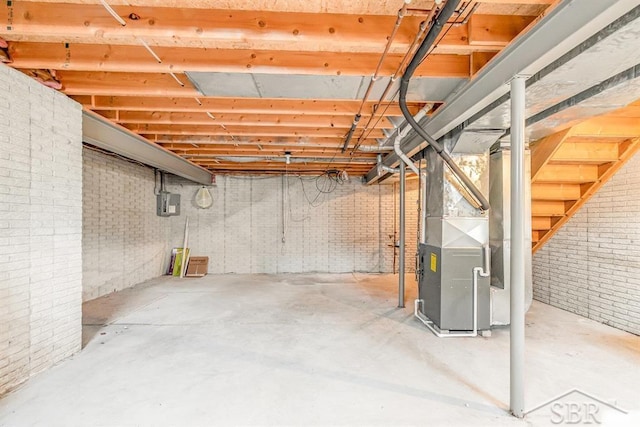 unfinished basement featuring brick wall and heating unit