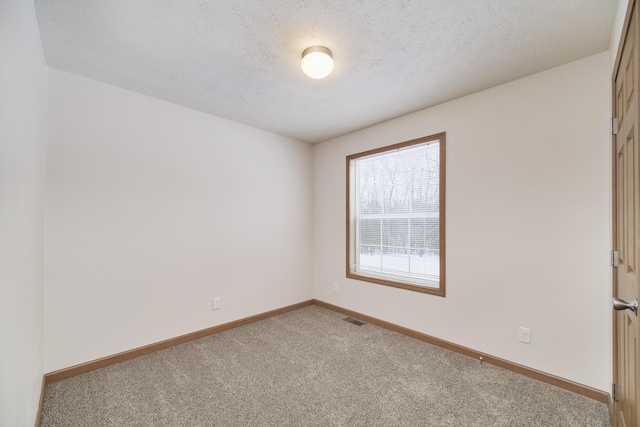 unfurnished room with visible vents, carpet flooring, a textured ceiling, and baseboards