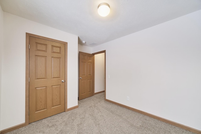 unfurnished bedroom featuring light colored carpet and baseboards