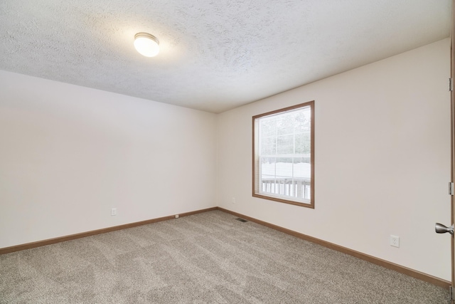 empty room with light carpet, visible vents, baseboards, and a textured ceiling