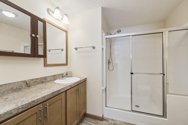 full bath featuring a textured ceiling, a stall shower, and vanity