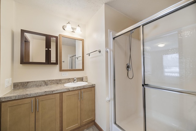 full bathroom featuring a stall shower, vanity, and a textured ceiling