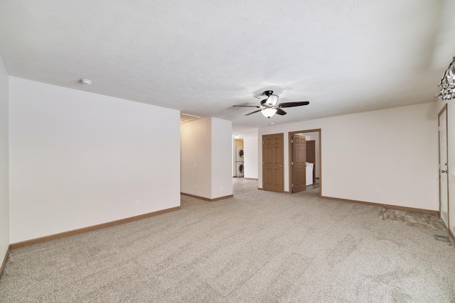 spare room featuring light carpet, ceiling fan, a textured ceiling, and baseboards