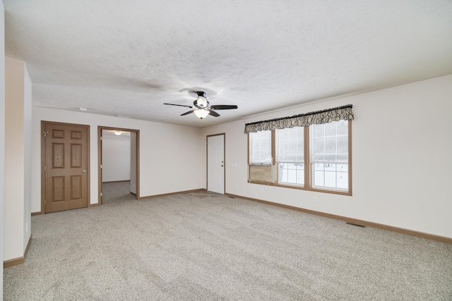 spare room featuring visible vents, a ceiling fan, carpet flooring, a textured ceiling, and baseboards