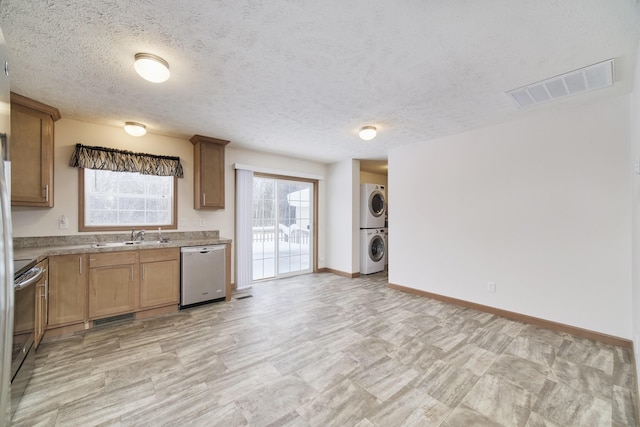 kitchen with stacked washer and clothes dryer, range with electric stovetop, visible vents, stainless steel dishwasher, and baseboards