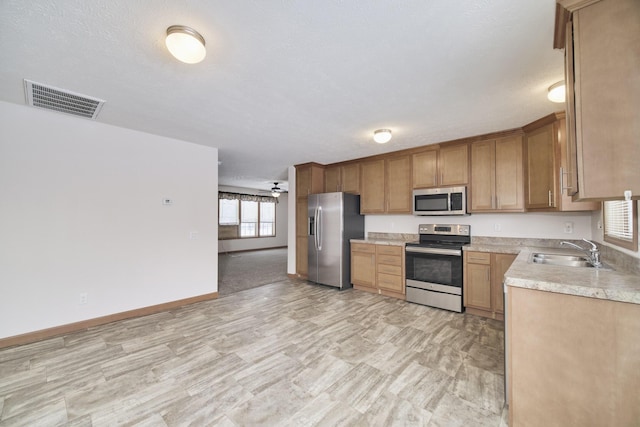 kitchen with light countertops, visible vents, appliances with stainless steel finishes, a ceiling fan, and a sink