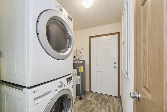 laundry room featuring stacked washer and dryer, laundry area, a textured ceiling, light wood-style floors, and water heater