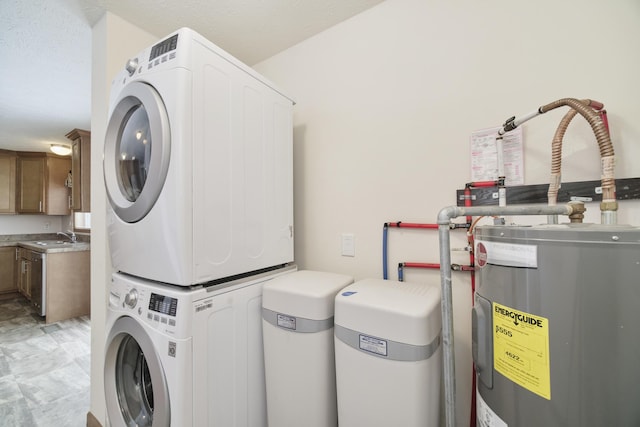 clothes washing area with laundry area, electric water heater, a sink, and stacked washing maching and dryer