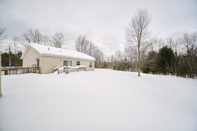 snow covered back of property with a wooden deck