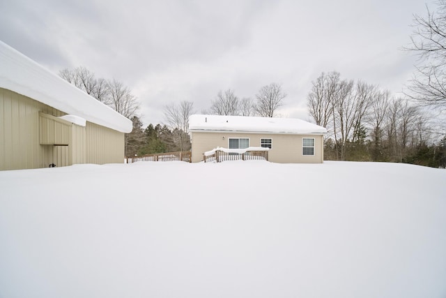 snow covered back of property featuring a deck