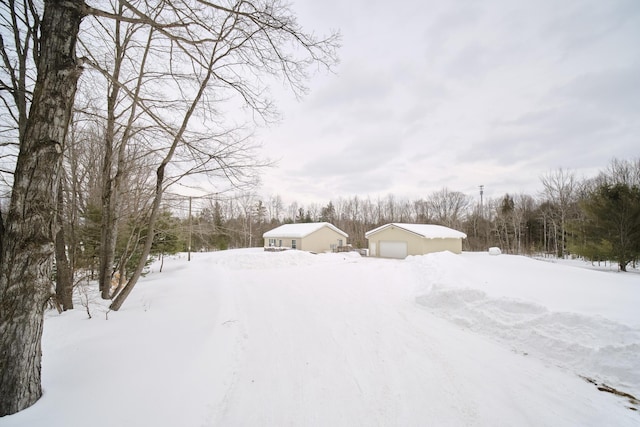 yard layered in snow featuring a garage and an outdoor structure