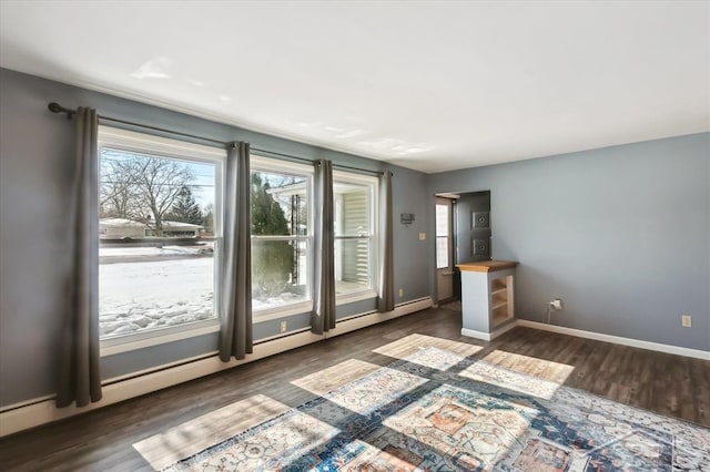 interior space featuring baseboards, baseboard heating, and wood finished floors