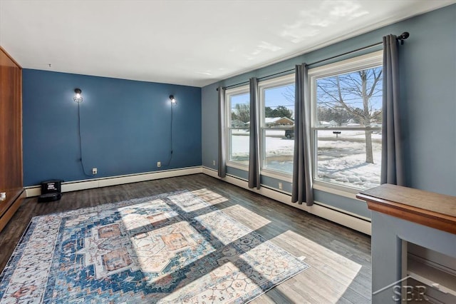 empty room with a baseboard heating unit, wood finished floors, and baseboards