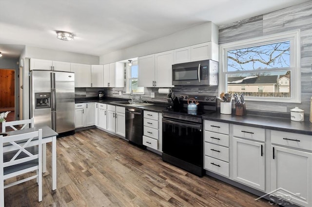 kitchen with stainless steel appliances, white cabinetry, dark wood-style floors, tasteful backsplash, and dark countertops