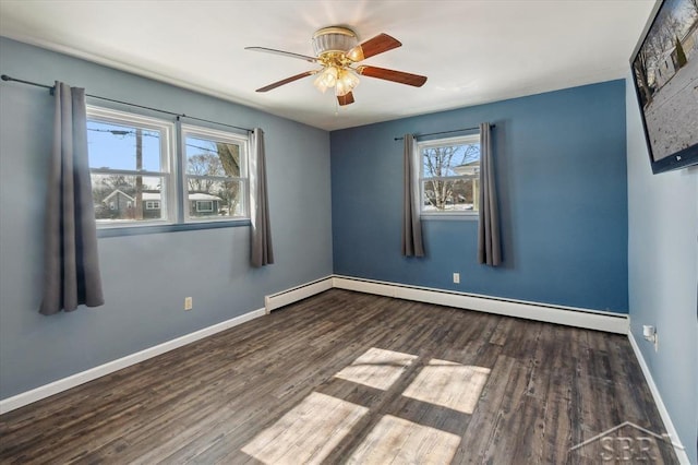 empty room featuring baseboard heating, wood finished floors, a ceiling fan, and baseboards