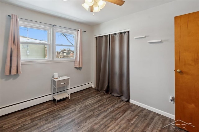 unfurnished bedroom with ceiling fan, dark wood-type flooring, a baseboard radiator, and baseboards