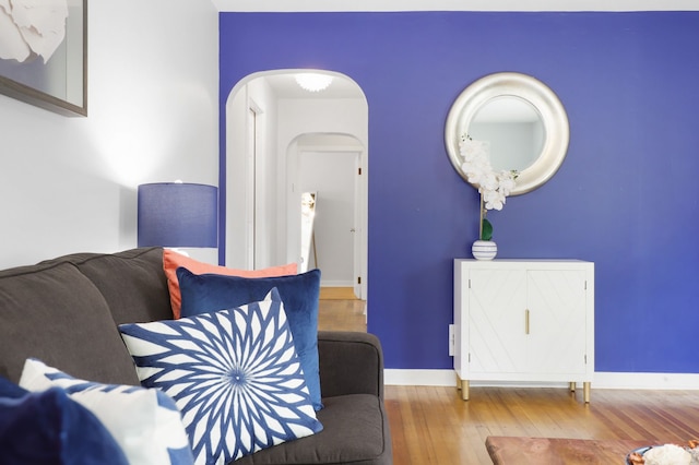 living room featuring arched walkways, wood finished floors, and baseboards