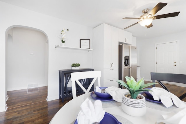 dining space with arched walkways, wood finished floors, visible vents, baseboards, and a ceiling fan