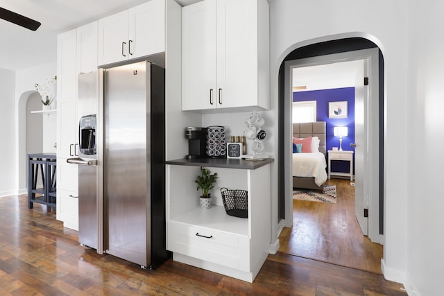 kitchen with dark wood-style floors, arched walkways, white cabinets, and stainless steel fridge with ice dispenser