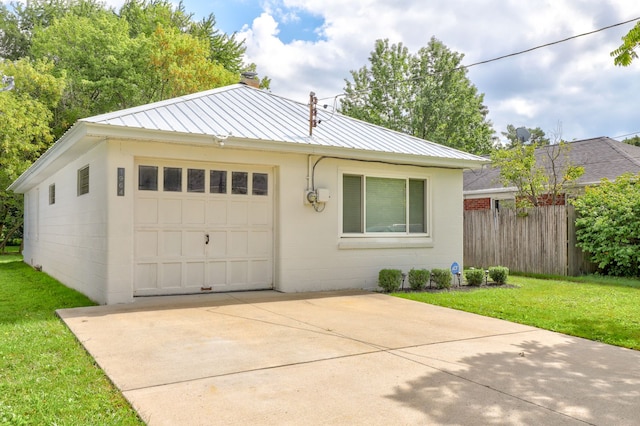 view of front facade with driveway, concrete block siding, metal roof, fence, and a front yard