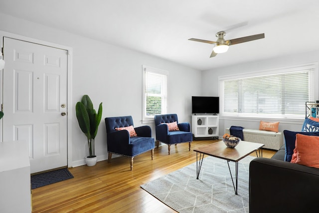 living room with ceiling fan, light wood-style flooring, and baseboards