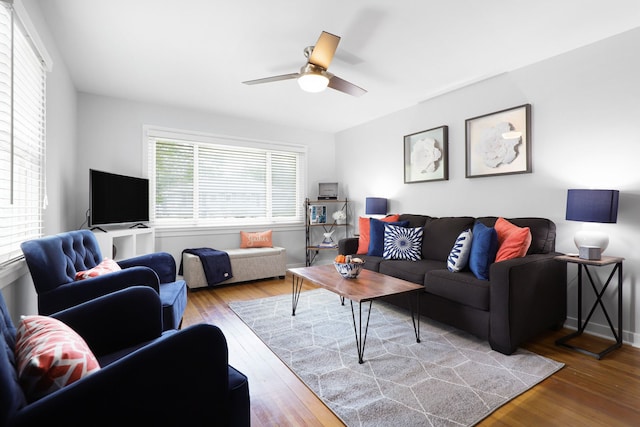 living room with ceiling fan, baseboards, and wood finished floors