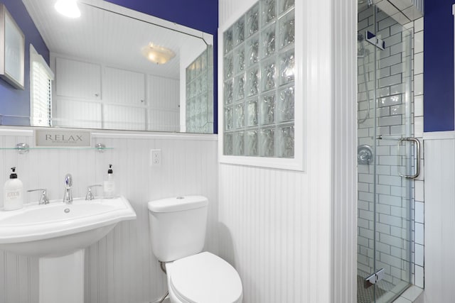 bathroom featuring wainscoting, a sink, a shower stall, and toilet