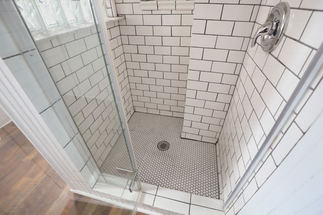 full bath with tiled shower and wood finished floors