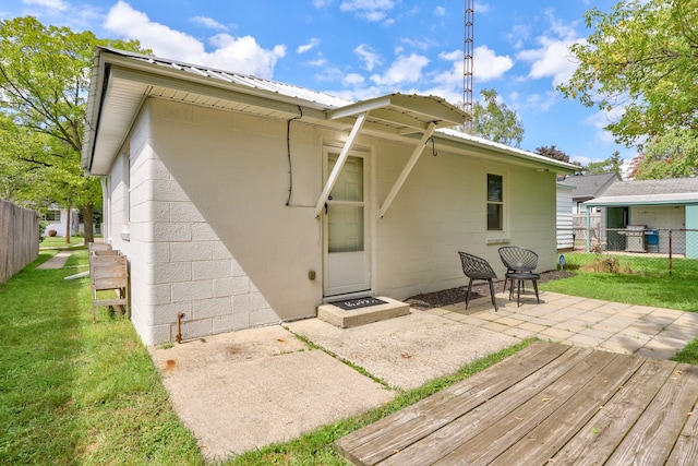 rear view of property with a patio, concrete block siding, metal roof, fence, and a yard