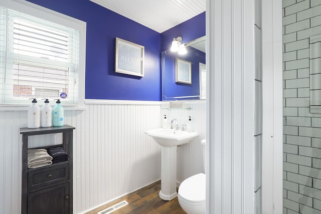 bathroom with toilet, wainscoting, wood finished floors, and visible vents