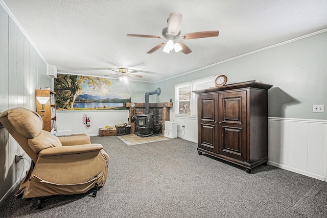 sitting room featuring a wood stove, a water view, carpet, a textured ceiling, and crown molding