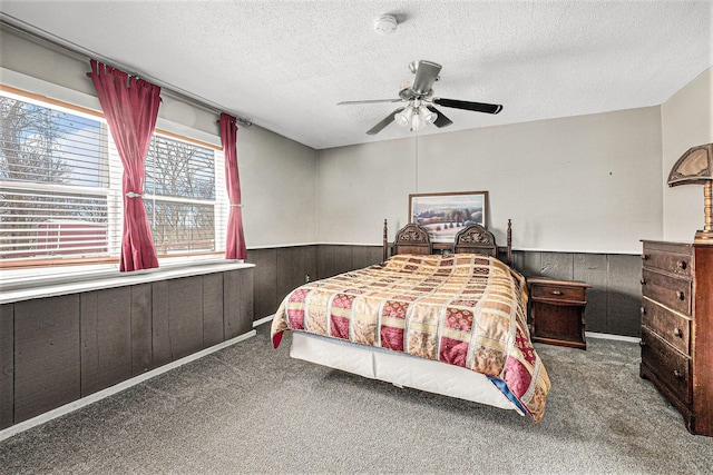 bedroom with carpet floors, wainscoting, wood walls, and a textured ceiling