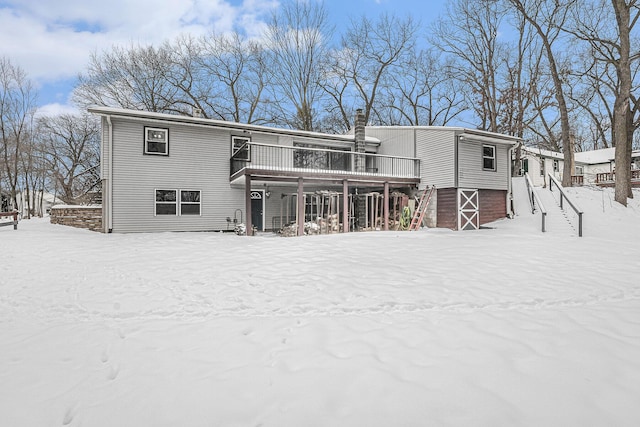 snow covered back of property featuring stairs