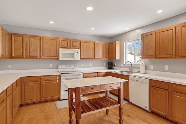 kitchen featuring light wood-style flooring, recessed lighting, white appliances, a sink, and light countertops