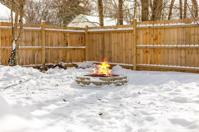 yard covered in snow with fence and a fire pit