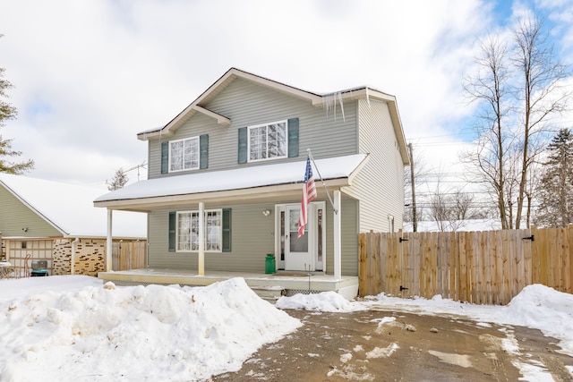 traditional-style home featuring covered porch and fence