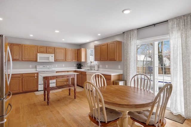 kitchen with white appliances, light countertops, light wood-style floors, a sink, and recessed lighting