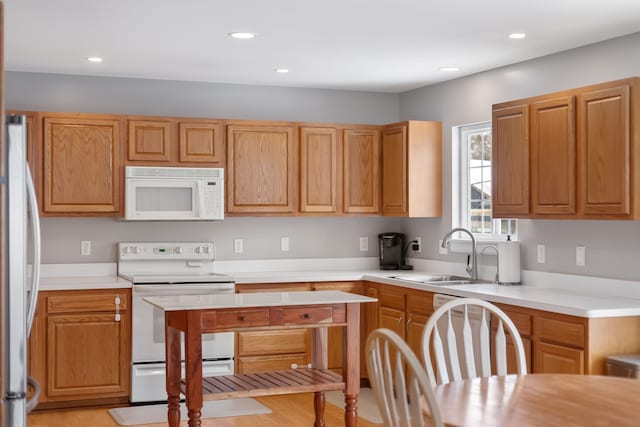 kitchen with white appliances, light countertops, and a sink