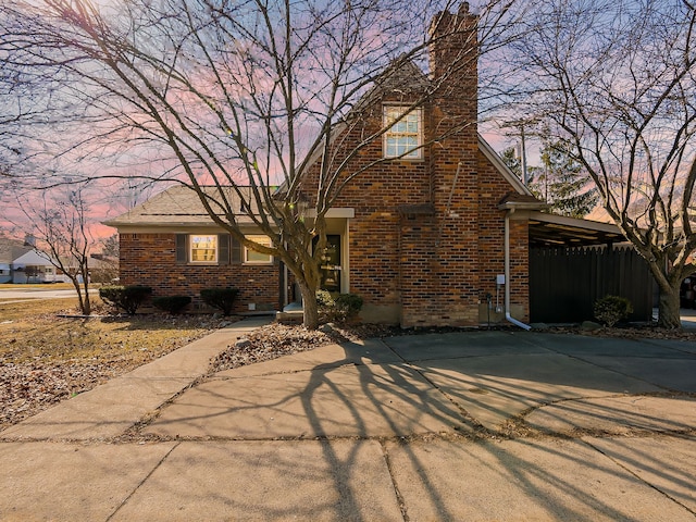 view of front of home with a chimney and brick siding