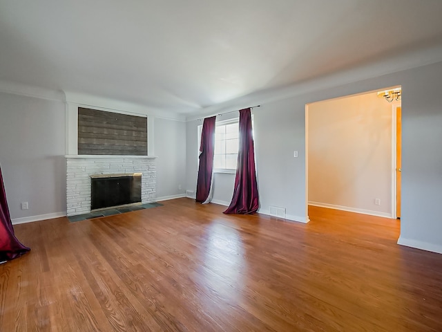 unfurnished living room with a fireplace, baseboards, and wood finished floors