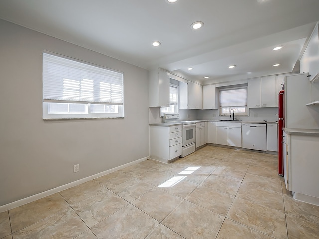 kitchen featuring light tile patterned flooring, a sink, white cabinetry, white appliances, and baseboards