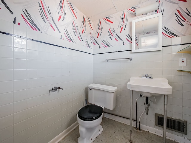 bathroom featuring toilet, speckled floor, visible vents, and tile walls