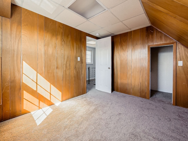 interior space featuring a paneled ceiling, carpet, and wooden walls