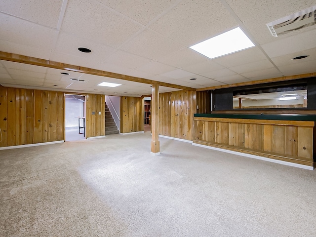 finished basement featuring visible vents, wood walls, carpet flooring, and stairs