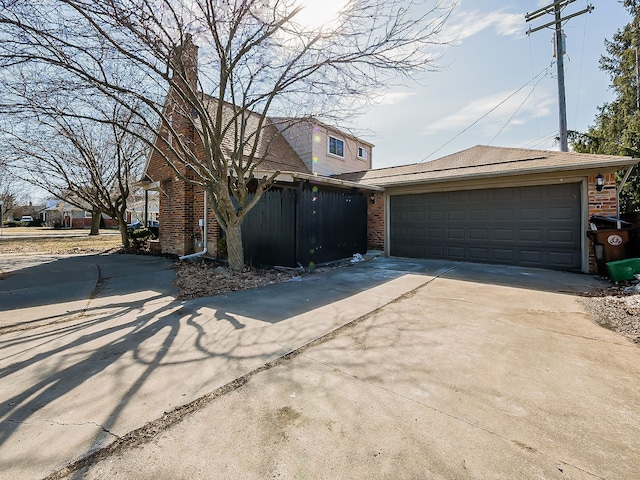 view of front of property featuring a garage, a chimney, concrete driveway, and brick siding