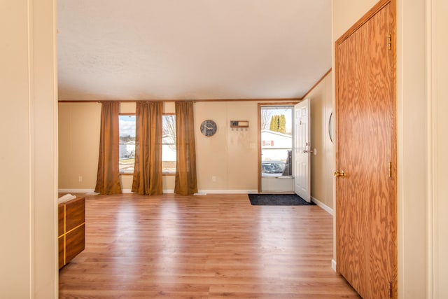 foyer entrance with ornamental molding, light wood-style flooring, and baseboards