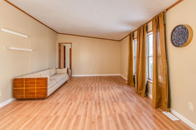 unfurnished room with crown molding, light wood-style flooring, and baseboards