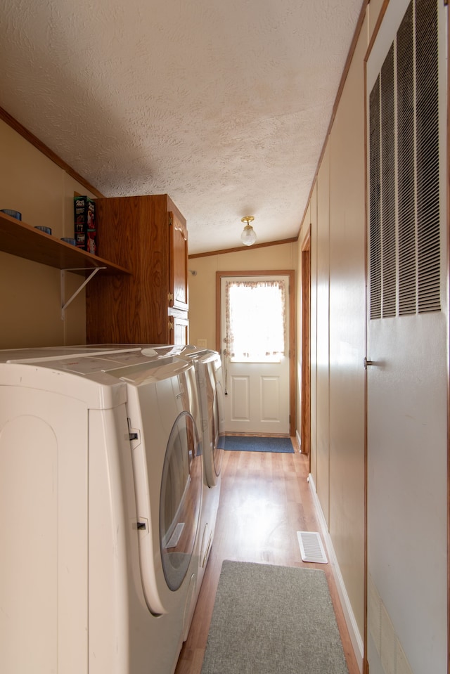 laundry area with cabinet space, light wood-style floors, washing machine and dryer, ornamental molding, and a heating unit